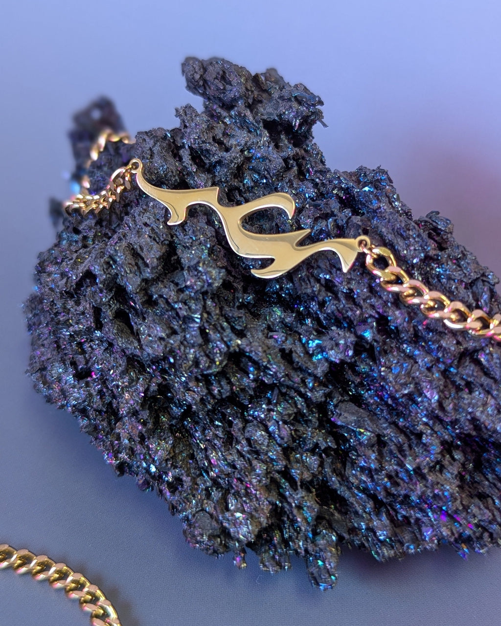 Gold necklace with a whale pendant on a textured blue surface